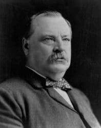 Portrait of a middle-aged man with a mustache wearing a dark suit and polka-dot bow tie, looking slightly to the right.